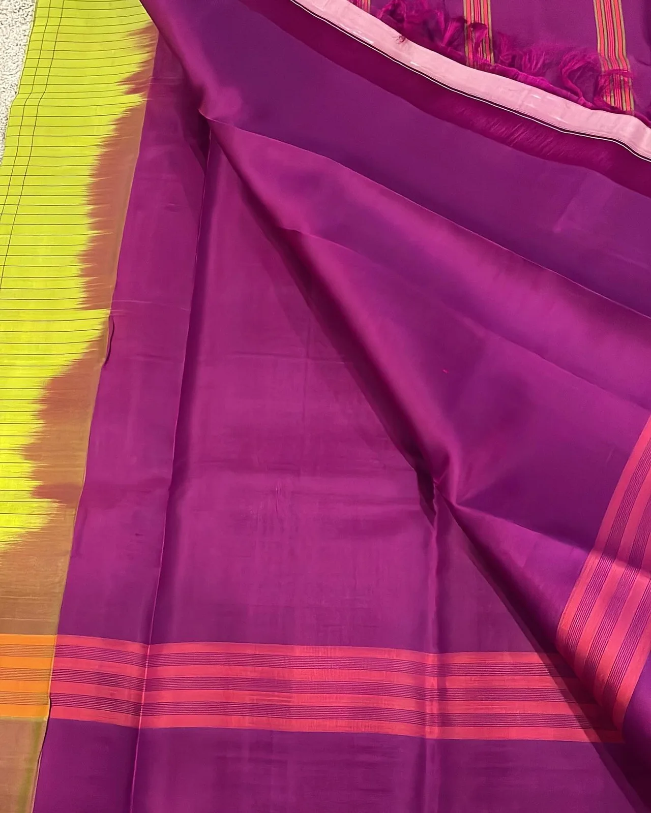 Close-up of the saree folds showing the dark magenta border meeting the parrot green checkered body.
